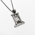 A guillotine pendant with a skull and chain on it.