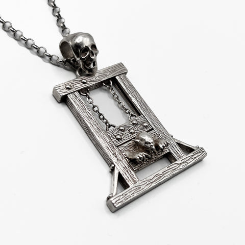 A guillotine pendant with a skull and chain on it.