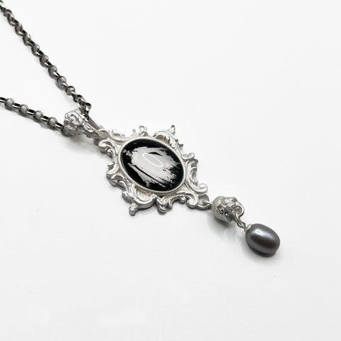 A necklace with a black and white image of a ghost.